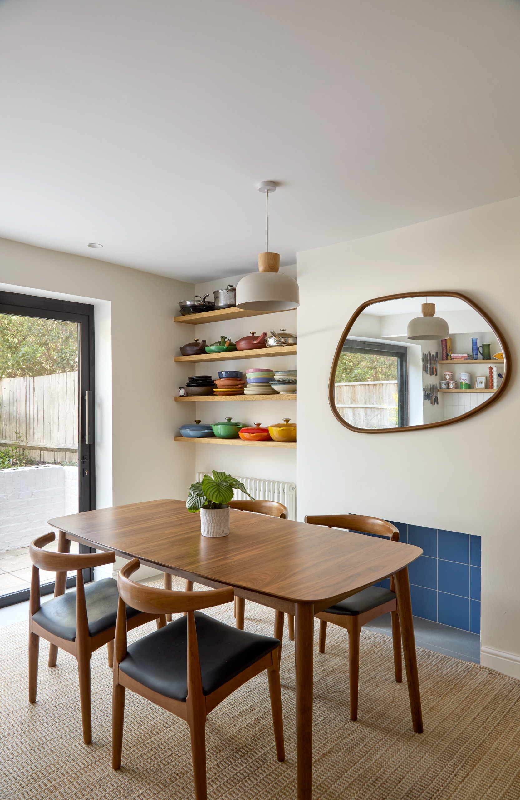 dining area with blue tiled fireplace and a curved mirror above