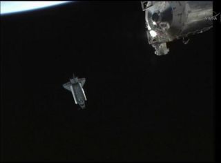 Shuttle Endeavour backs away from the International Space Station after undocking from the outpost for one last time on May 29, 2011 during the STS-134 mission. This view was recorded by a camera on the exterior of the space station, part of which is visi
