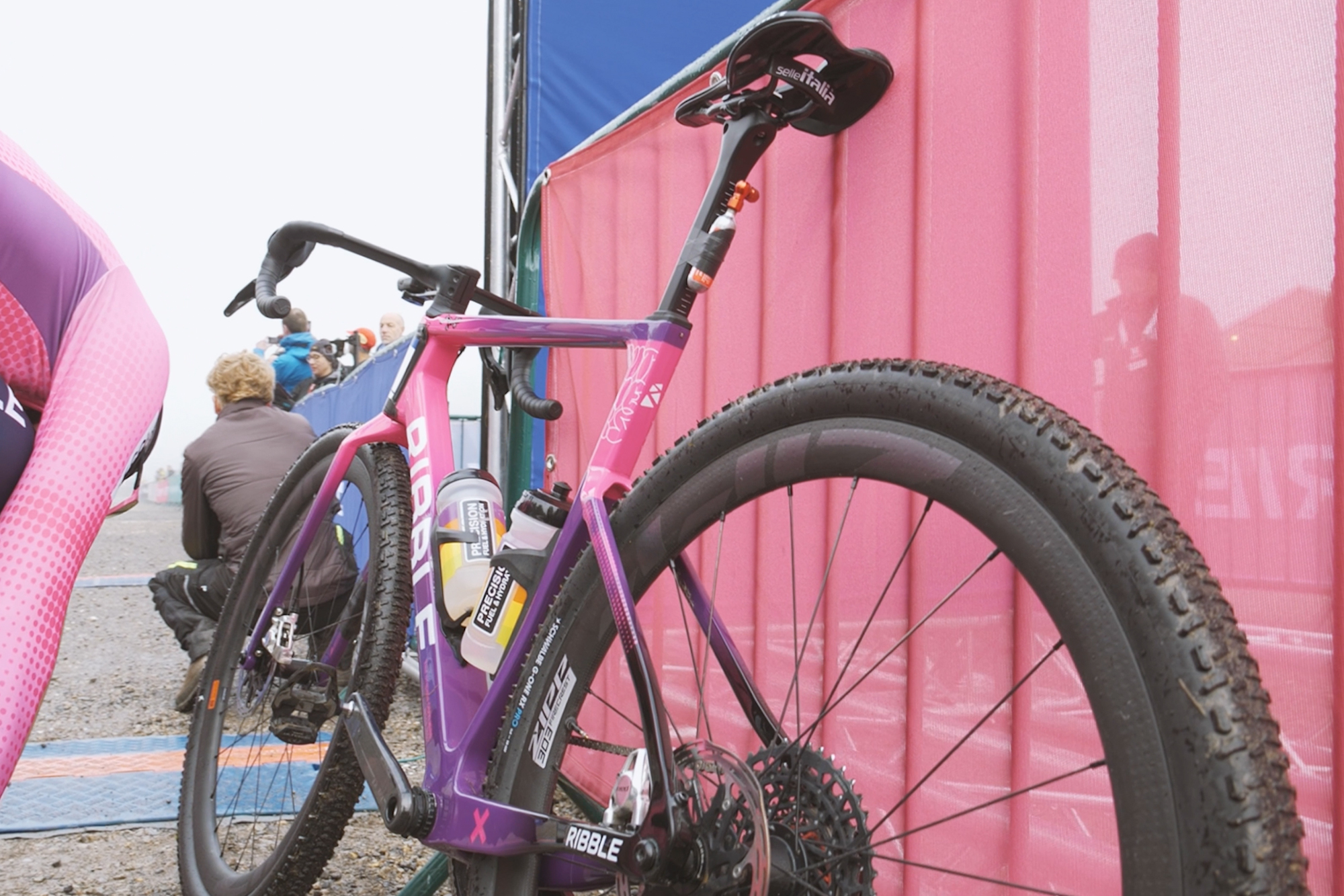 A pink and purple Ribble gravel bike being used by both male and female athletes on a misty day at British Gravel Champs