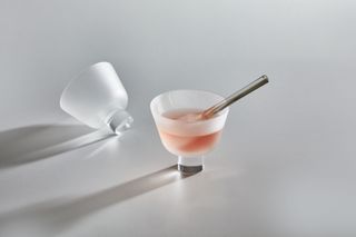 Two frosted glass cups with pink liquid and a small spoon inside one of them