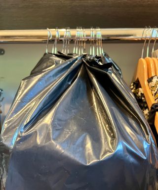 Hanging clothes wrapped in a trash bag