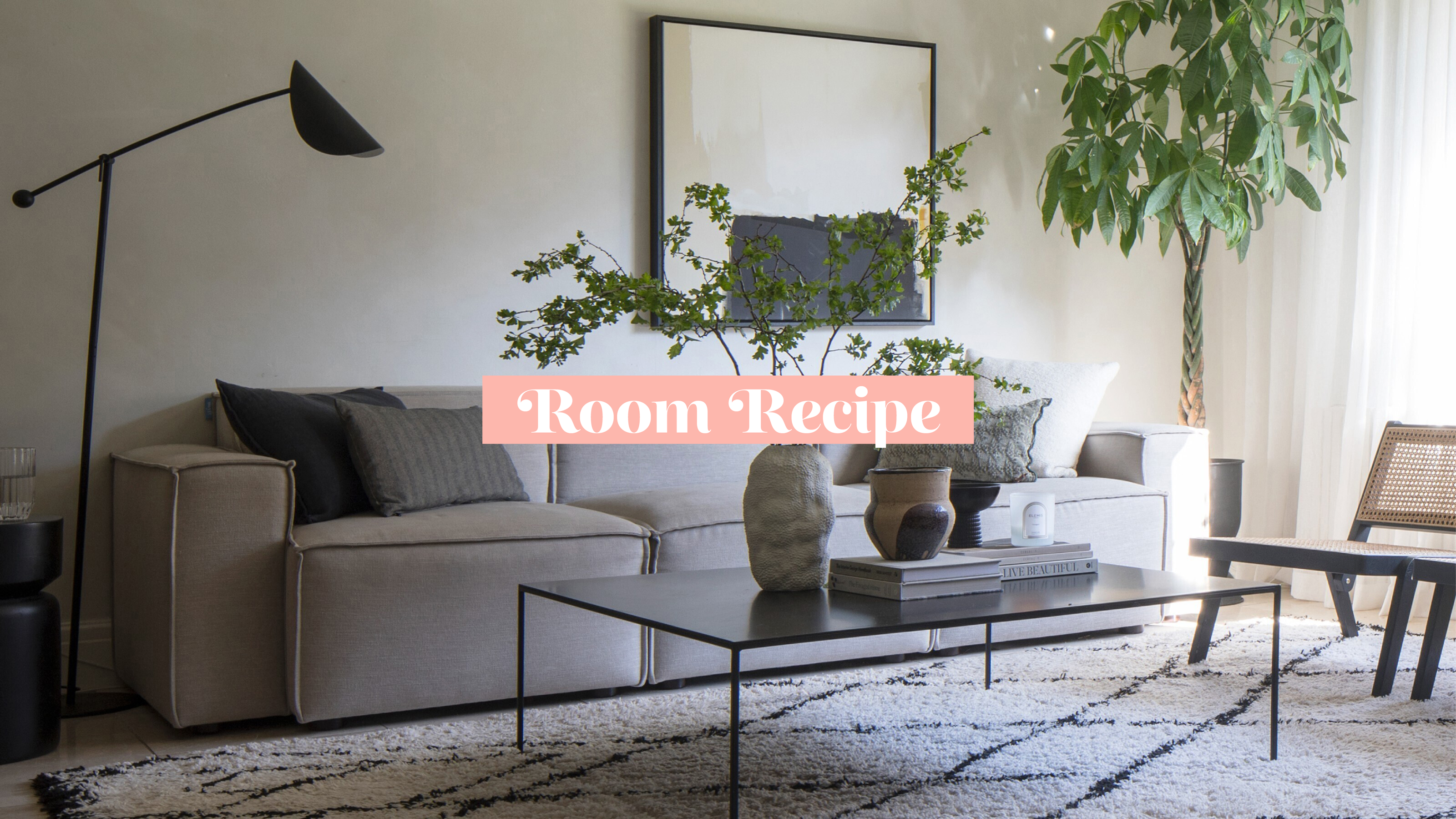 Japandi living room with beige sofa, coffee table, wooden chair and floor lamp to the left, plant and picture on wall to the right, berber rug on floor