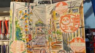 Inside the artist sketchbook; watercolour street sketch in a book surrounded by paints