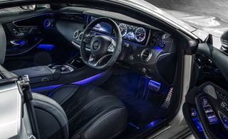 Looking inside the car, there is black leather interior and a black dashboard illuminated in blue