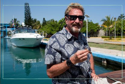 a medium shot of John McAfee posing next to a yacht