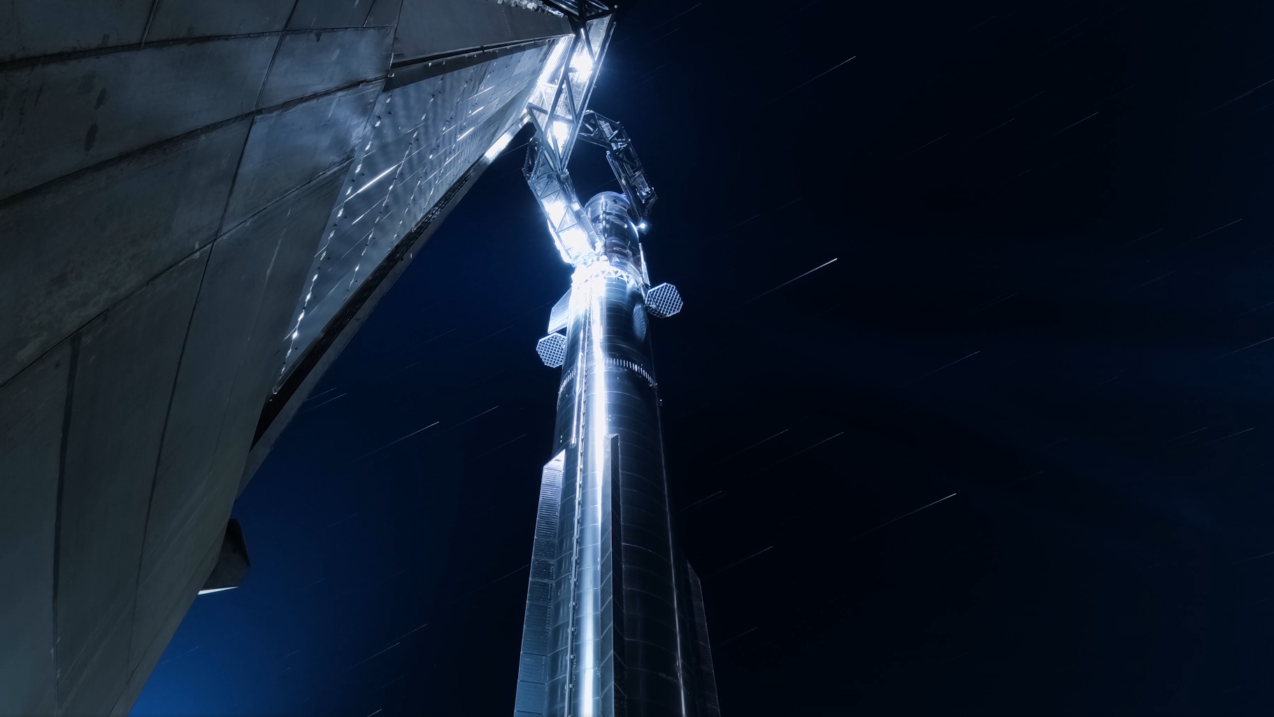 A giant chrome rocket stands against a starry night sky.