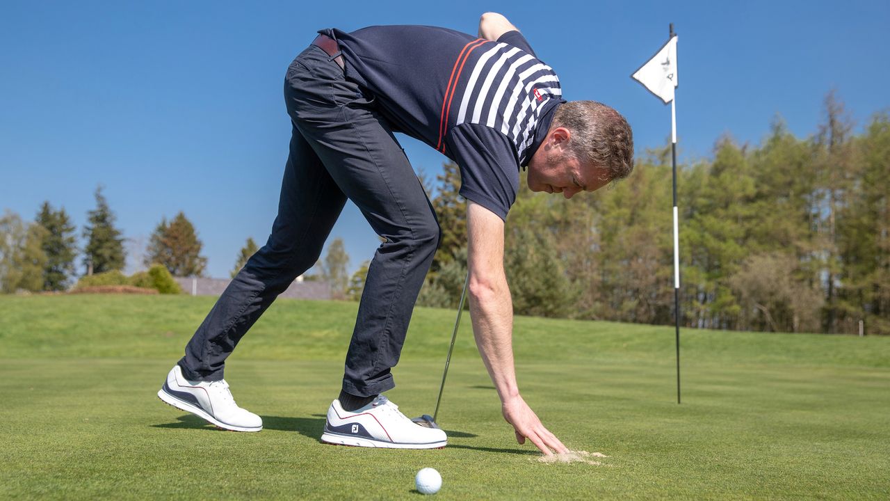 Brushing sand from the putting green with your hand