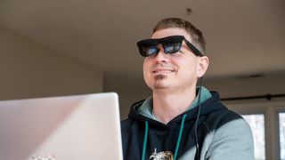 Wearing a pair of Xreal One smart glasses while working on a laptop