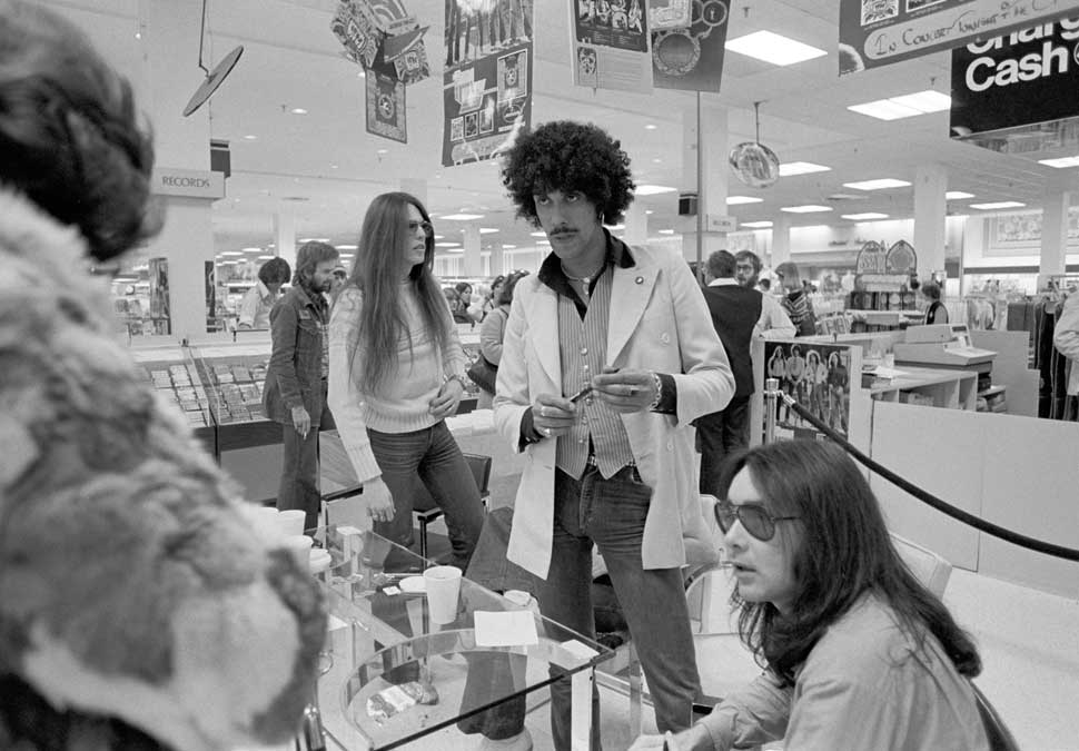 Guitarist Scott Gorham, singer/bassist Phil Lynott and drummer Brian Downey (seated) of Thin Lizzy greet fans during Thin Lizzy in-store Appearance at Northlake J.C. Penney's on February 21, 1977 in Atlanta, Georgia, United States