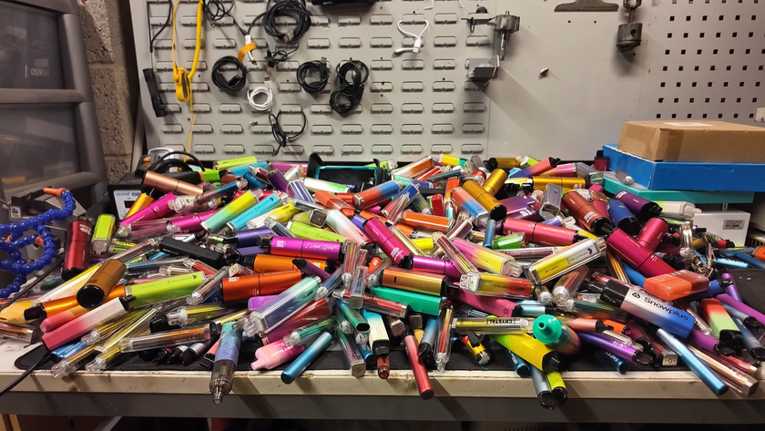 A workbench completely covered in colourful, single-use vapes.