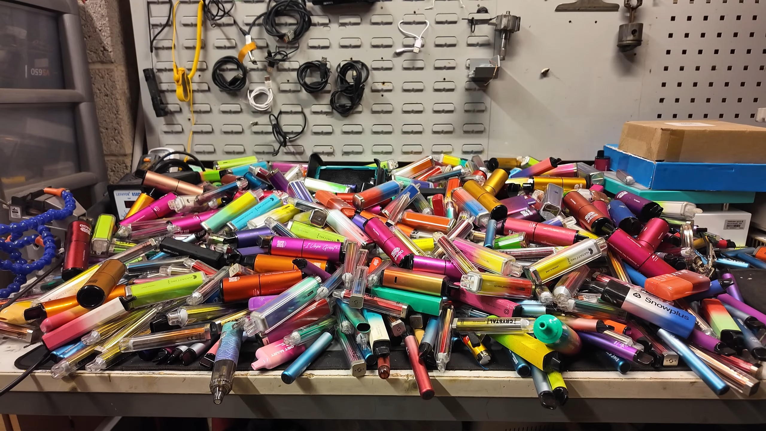 A workbench completely covered in colourful, single-use vapes.