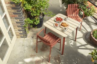 Sustainable outdoor furniture by Very Good and Proper in red, including a chair with recycled and hemp fiber seat and Accoya wood table top