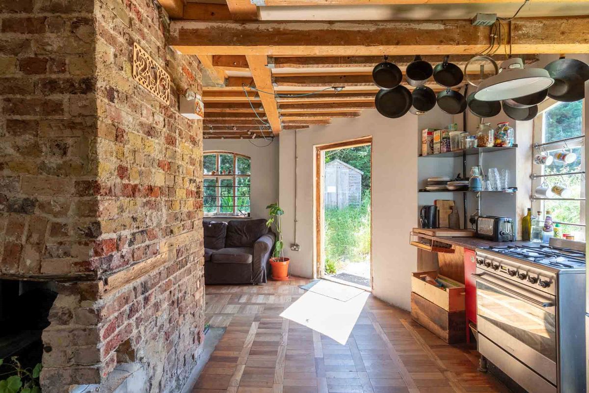 Wooden beams are visible on the roof with the kitchen being on the side of the open plan living room