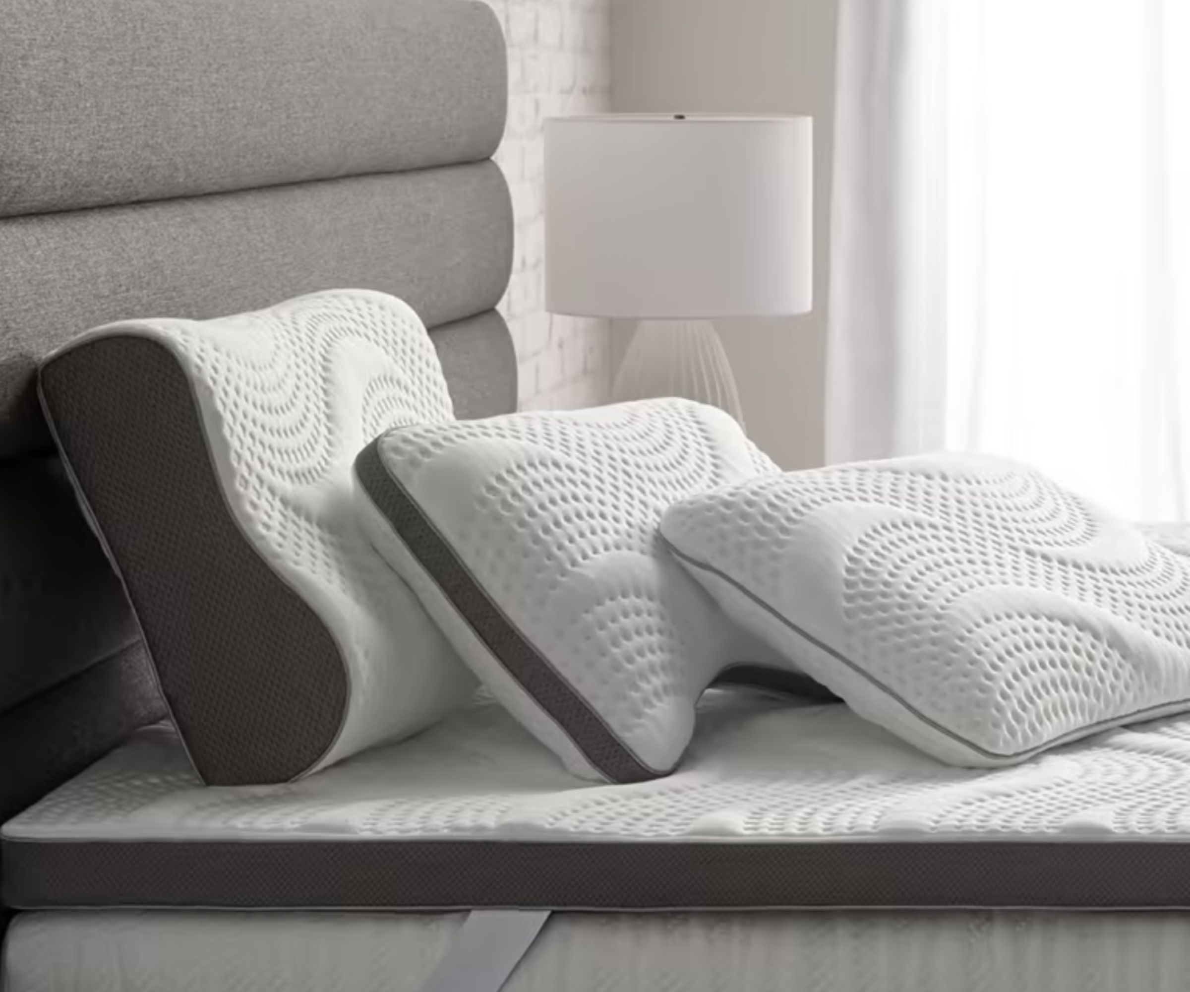 Three different shaped pillows on a bed