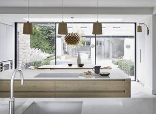white kitchen with wooden cabinetry, double kitchen islands and wooden pendants