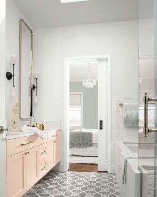 white bathroom with pale pink sink cabinet; walls painted in Decorator's White paint color by Benjamin Moore