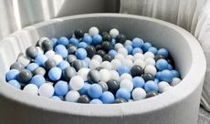 Soft play equipment from whatkidslovethemost – grey ball pit with blue, grey and white balls inside – inside a grey living space