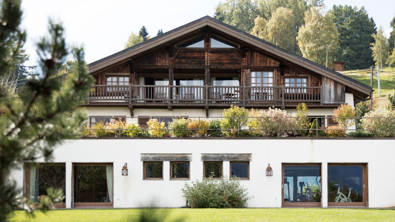 Balcony garden ideas featuring bushy plants along the balcony of a chalet-style dark wooden home.