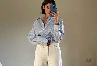 Woman in blue button-down and white jeans.