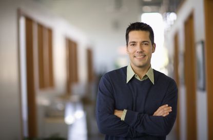 Businessman standing in hallway of office, arms crossed