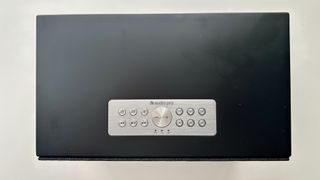 The top panel of the Audio Pro Addon C10 MkII wireless speakers, showing a mostly black body, but with a silver panel with 12 buttons and a dial. These include playback controls and some numbered buttons for 'favorite' music shortcuts