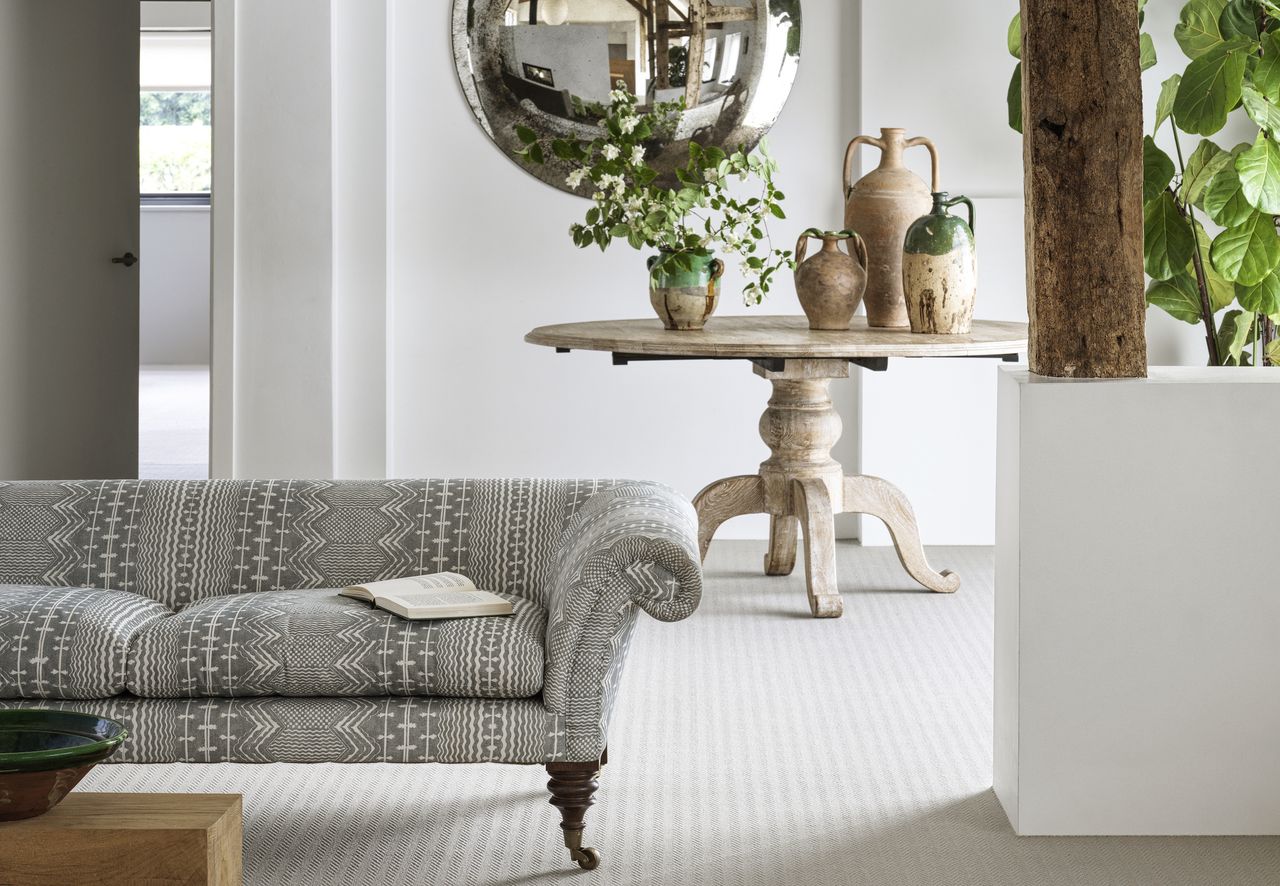 Living room with beige carpet and large circular mirror