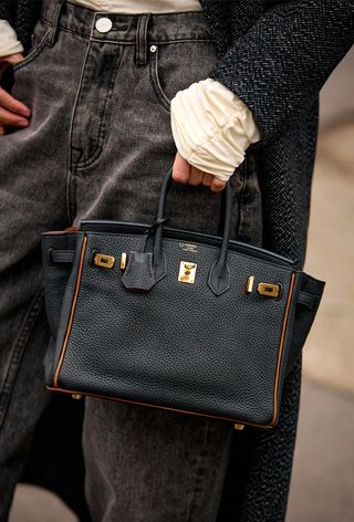 a street-style photo of a woman carrying a Hermés bag in a story about how to buy an hermés bag