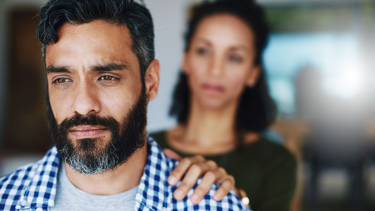 Woman with her hand on her husband&#039;s shoulder, supporting him as he suffers from hearing loss issues