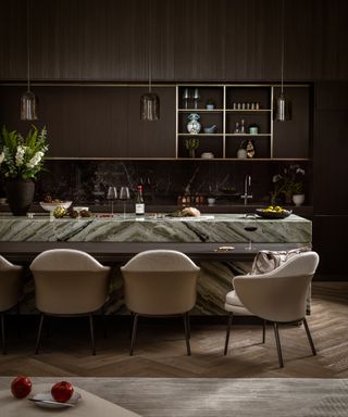 kitchen with green marble breakfast bar, leather and fabric dining chairs, dark wood cabinetry and smoked glass pendants