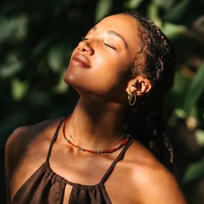 woman with eyes closed leaning face into the sun