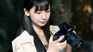 Woman holding Nikon camera with Meike 85mm f/1.8 Pro lens attached