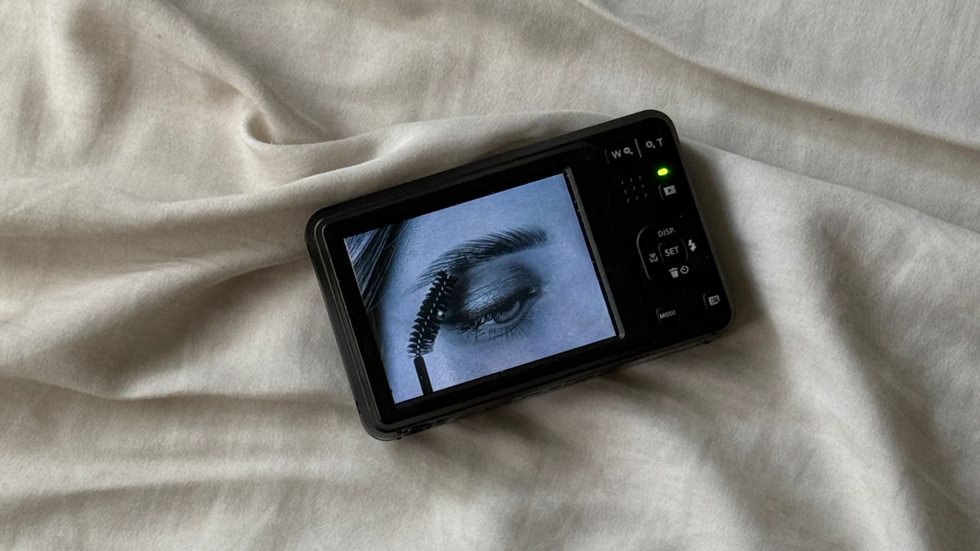 An image of a digital camera on a bedsheet.