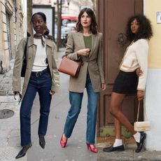 Influencer Sylvie wears a trench coat with a white top and blue jeans. Jeanne Damas wears a blazer with blue jeans and red pumps. Influencer Emmanuelle wears loafers with a black mini skirt and white cardigan. 
