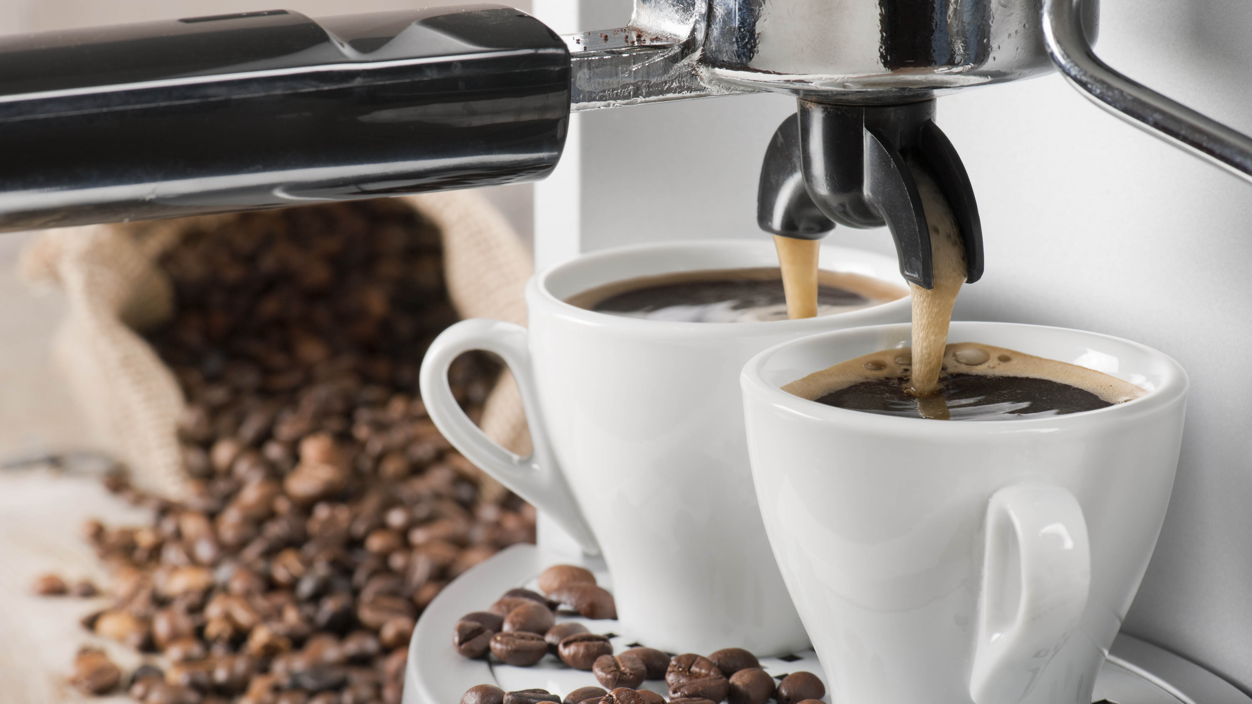 Two white coffee cups on machine