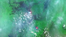 A satellite photo showing two bright red spots in a green landscape