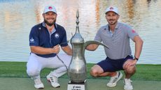 Tyrrell Hatton (left) and his caddie Hugo Dobson pose next to the Dubai Desert Classic trophy after their win in 2025