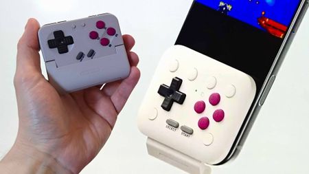Close up of 8Bitdo FlipPad on right attached to phone next to hand holding Gamesir Pocket Taco on left.