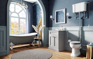 blue bathroom with arched window with a freestanding bath and elegant wall panelling to show a key bathroom trend 2023