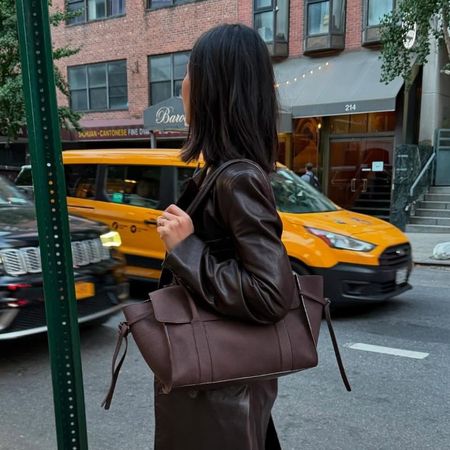 woman wears cream knit sweater and burgundy tote bag