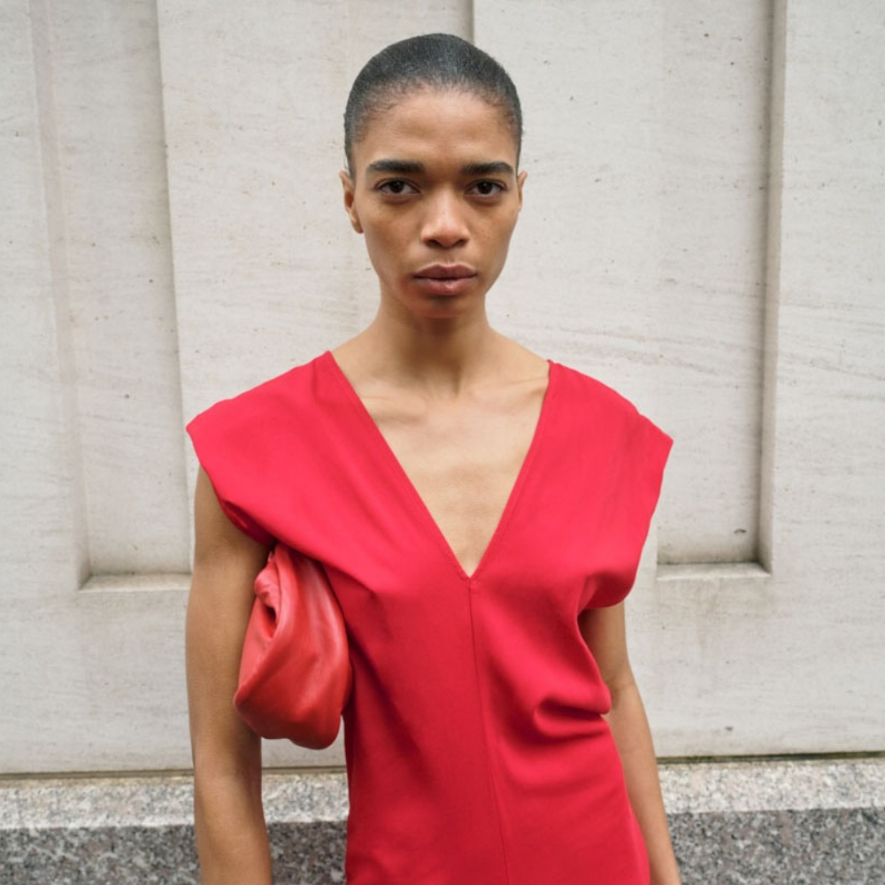Woman wearing red St. Agni dress and hand bag in front of marble wall