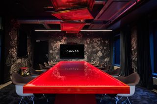 Red glossy table in dark room at Lynk & Co Offices, Gothenburg, by New Order Arkitektur