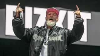 Fred Durst smiling on stage in a pink cap