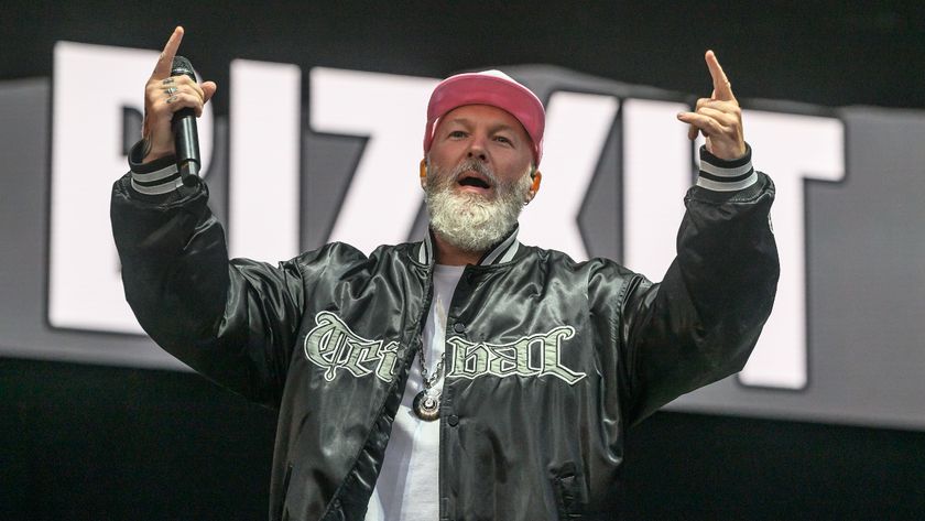 Fred Durst smiling on stage in a pink cap