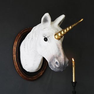 white unicorn head with candle and grey wall
