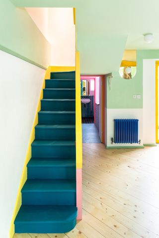 color block house with blue staircase and yellow stair rail