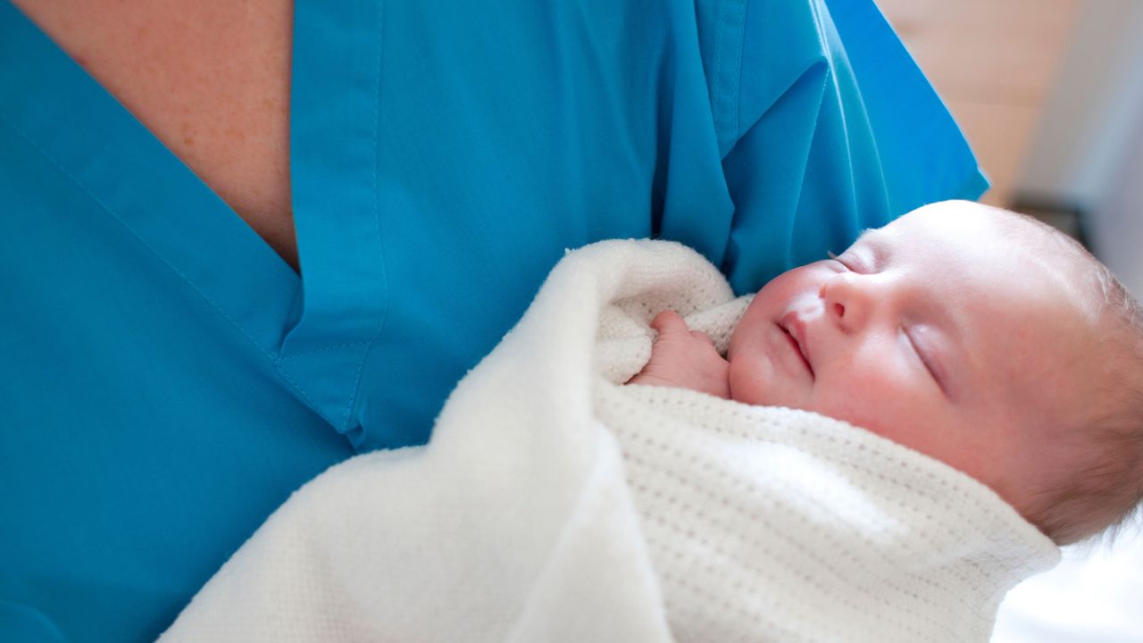 A midwife holding a newborn baby after its Apgar score test