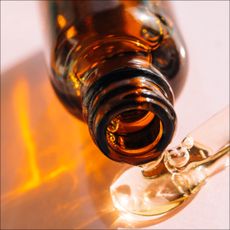 A close up of a bottle releasing a serum