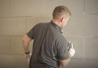 man applying wall grout to tile