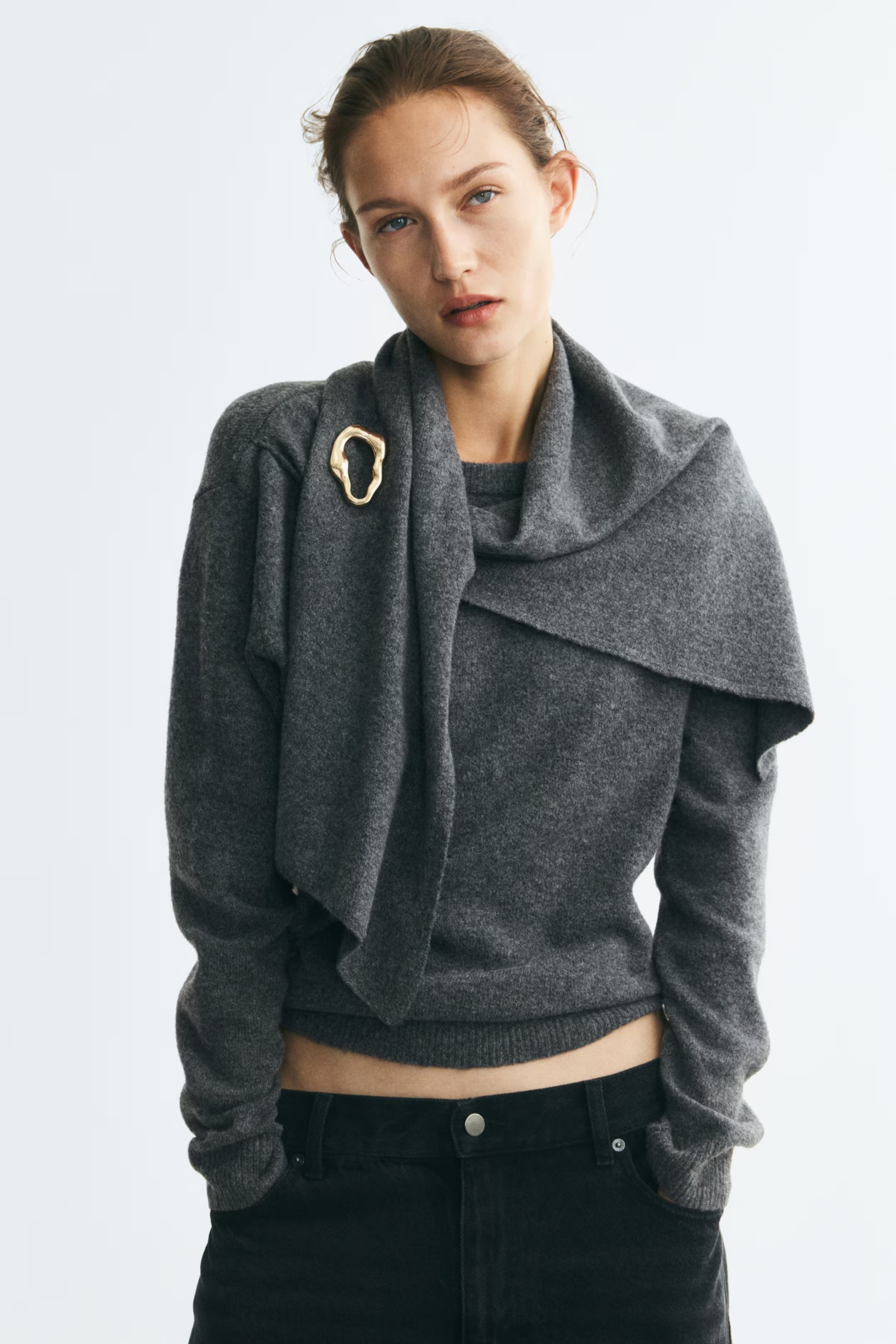 An H&amp;amp;M model wearing a draped grey sweater with a brooch
