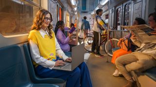 A woman on a bus using a Snapdragon X Elite laptop